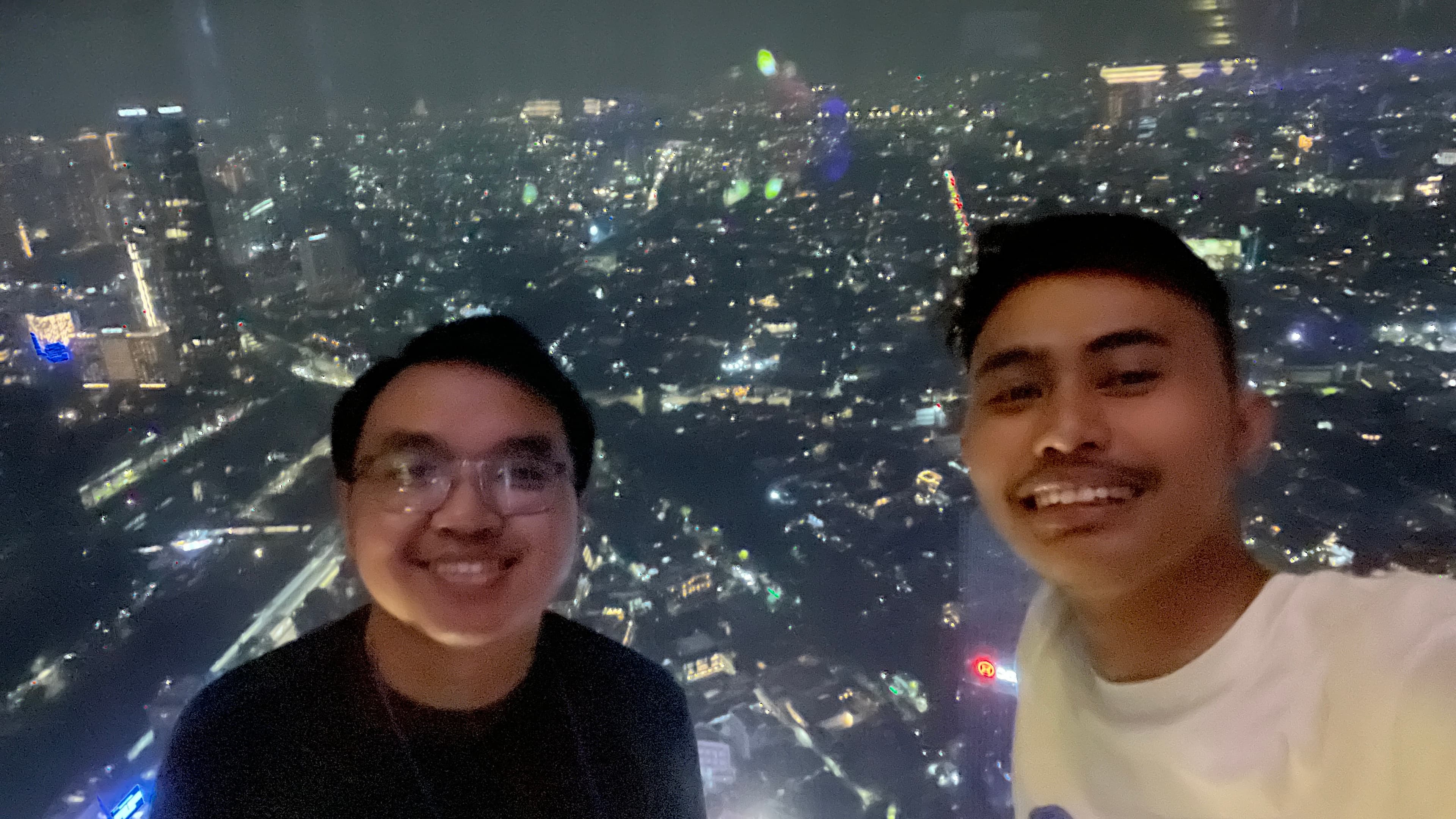 Fathin and Robby with the Jakarta skyline at night
